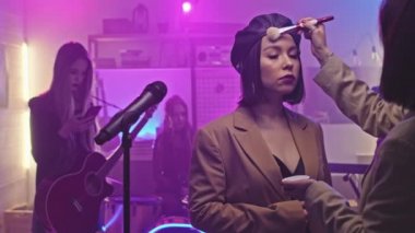 Tanımlanamayan makyaj sanatçısının, rock müzik grubunda çalan ve gece kulübündeki konsere hazırlanan genç ve çekici kadın şarkıcıya makyaj yaptığı orta PAN yavaşlığı.