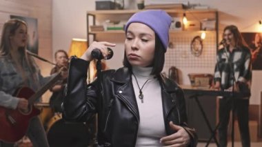 Ağır çekimde, modaya uygun giysiler içinde çekici genç bir kadının mikrofon içinde rock müzik söylerken acınası bir şekilde kameraya baktığı bir sahne.