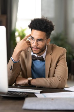 Dalgın, genç bir Afro-Amerikan hedef uzmanı. Kıvırcık saçlı, masada oturuyor ve bilgisayardaki araştırma verilerini incelerken başını öne eğiyor.