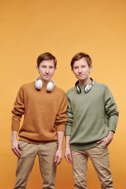 Boynunda kablosuz kulaklıkla parlak arka planda duran gülümseyen genç gençlerin portresi.