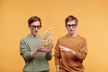 Üç boyutlu gözlüklü, film seyretmeye hazır genç kardeşlerin portresi, biri patlamış mısır fırlatıyor, yavaş çekim etkisi.