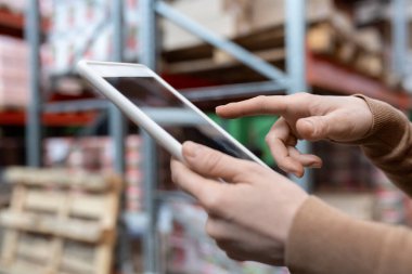 Depodaki sevkiyattan önce dijital tablet kullanarak malların miktarını inceleyen tanımlanamayan kadının yakın çekimi