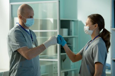 Ameliyat için hazırlanırken kel cerrah asistanıyla yumruk tokuşturuyor.