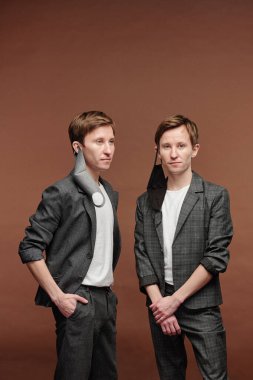 Maskeli, kulaklarında kahverengi arka planda duran kendinden emin gençler.