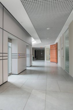 Zemin fayansları ve duvarlarında paralel çizgiler olan boş iş merkezi koridoru, minimalist tasarımların karışımı