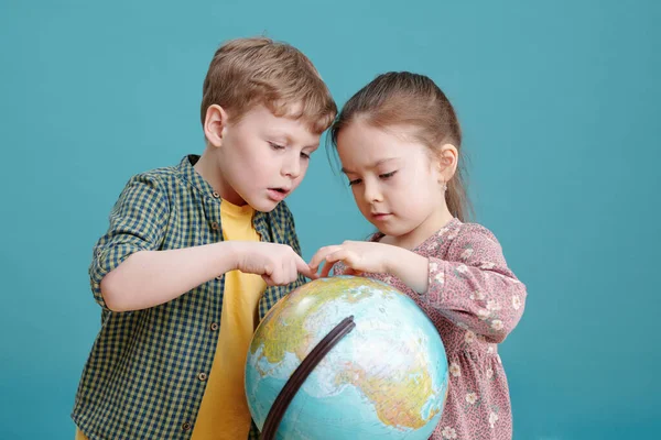 Two Little Children Examining Big Globe Together Standing Blue Background — Stock Photo, Image