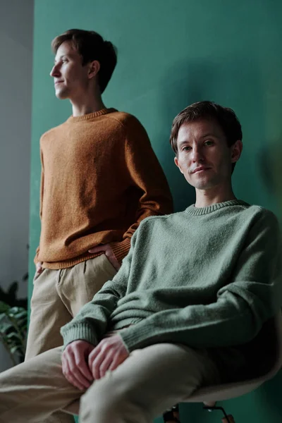 Retrato Hombre Joven Contenido Suéter Verde Sentado Silla Posando Contra — Foto de Stock