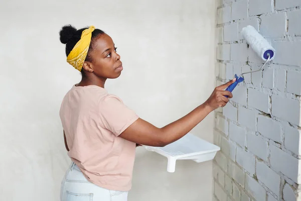 Jovem Fêmea Africana Séria Com Paintroller Canto Frente Parede Tijolo — Fotografia de Stock
