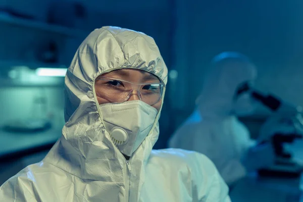 亚洲年轻化学家穿着防护服和眼镜在实验室工作时看着相机的画像 — 图库照片
