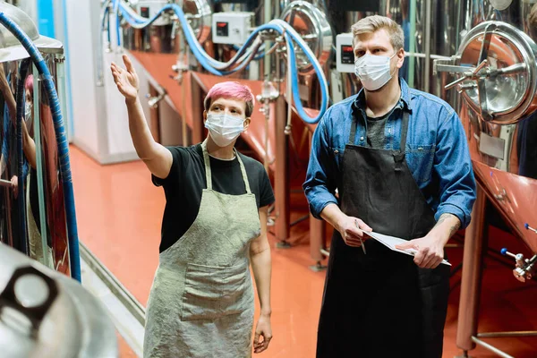 Dois Jovens Cervejeiros Máscaras Protetoras Discutindo Qualidade Novo Equipamento Produção — Fotografia de Stock