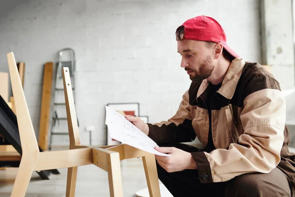 スタジオ またはフラット内の木製の椅子を組み立てながら 指導付きの紙を見て現代的な家具アセンブリの専門家 — ストック写真