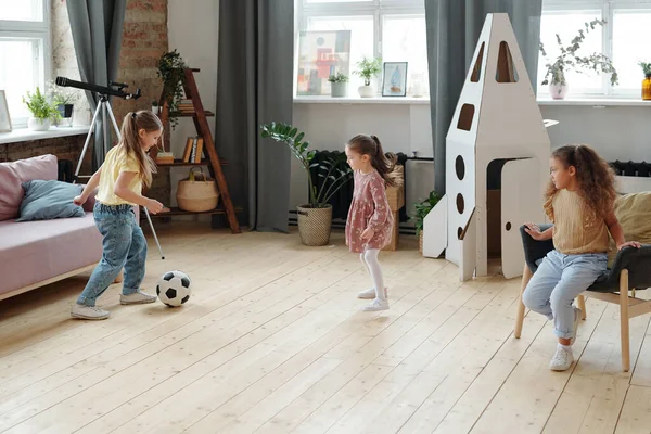 Group of little girls playing football together in the room at home