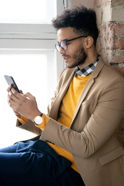 Serious Young Bearded Man Eyeglasses Sitting Window Sill Texting Message — Stock Photo, Image