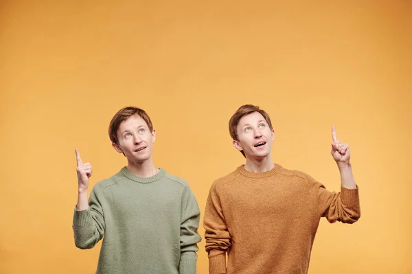 Sorprendido Jóvenes Preadolescentes Suéteres Colores Pie Sobre Fondo Naranja Apuntando — Foto de Stock