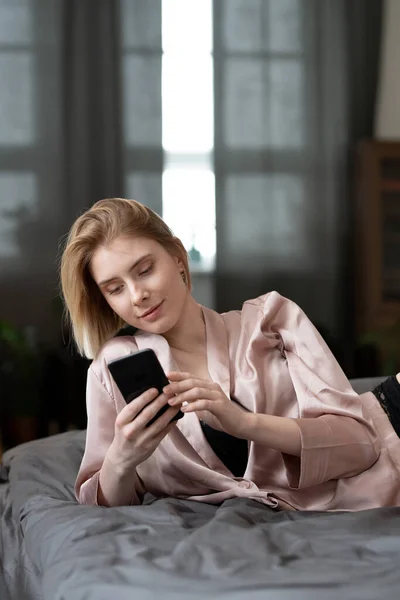 Gyönyörű Pizsamában Fekszik Ágyán Üzenetet Mobiljára Szobában — Stock Fotó