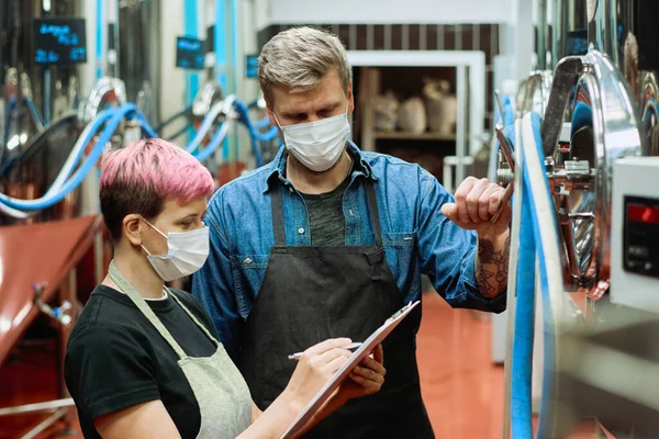 Dos Jóvenes Cerveceros Ropa Trabajo Máscaras Protectoras Discutiendo Notas Portapapeles —  Fotos de Stock