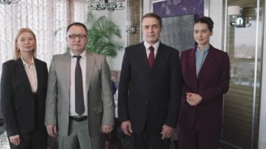 İki Asyalı ve Kafkasyalı siyasi temsilcinin orta PAN yavaş portresi ve onların kadın asistanları modern konferans odasında kameraya bakarak resmi olarak giyinmişler.