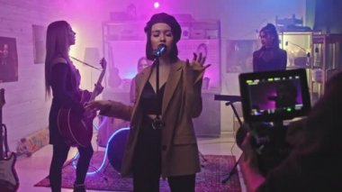 Genç bayan rock grubunun neon ışıklarıyla sahnede kalırken kaydettiği müzik videosuyla video operatörünün orta yavaşlığı.