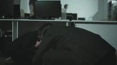 İş adamı ve iş kadınının el kamerasında, masaların arkasına çömelmiş ve ofislerinde zombilerden saklanırken çekilmiş. Onlar bir plan kuruyorlar.