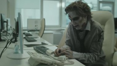 Korkunç SFX makyajlı zombi işadamının el kamerasıyla telefon etmeye çalışırken masaya oturup çığlık atması.