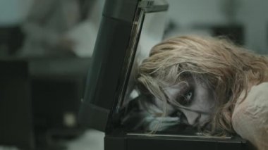 Beyaz lensli ve fotokopi makinesinde yatan SFX makyajlı genç zombi kadının PAN fotoğrafı.