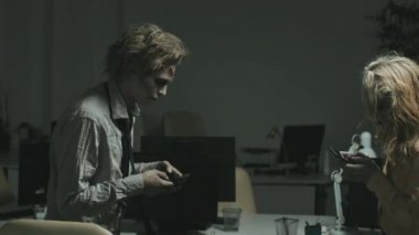 Zombi kadın ve adamın yavaş çekimleri cep telefonlarına bakıyor ve masaların arasında yürürken birbirlerine çarpıyorlar.