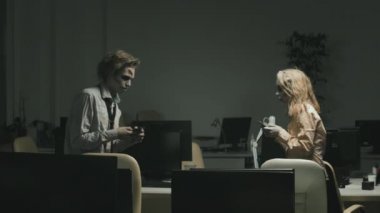 Zombi adam ve kadının cep telefonlarını tutarken ve masaların arasında yürürken birbirlerine çarptıkları orta boy bir fotoğraf.