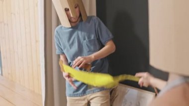 Kartondan miğfer takmış, kız kardeşiyle oyuncak kılıçlarla kavga eden, modern kır evinde eğlenen 12 yaşında tatlı bir kız.