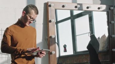 Güneşli bir günde havadar stüdyoda erkek moda tasarımcısının tabletli PAN yavaş portresi.