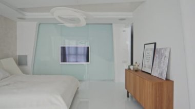 Minimalist tarzda, beyaz büyük boy yataklı ve parlak duvarlı televizyonlu modern şık yatak odası çekimleri yapmayan insanlar.