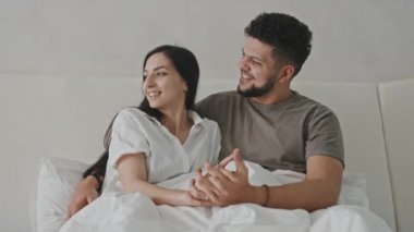 Orta halli, genç İspanyol bir çiftin sabahları yatakta el ele tutuşup pencereye bakarken iyi vakit geçirdiği bir fotoğraf.