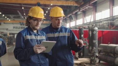 Kıdemli erkek yöneticinin, elinde dijital tablet tutan sakallı bir adamla fabrika tesisi üzerinde yaptığı çalışmaları tartıştığı orta derece bir yavaşlama.