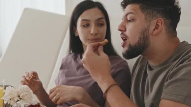 Romantik bir çiftin orta ölçekli yakın çekimi. Yeni evli, kahvaltı yapan ve yatakta sohbet eden bir çift.