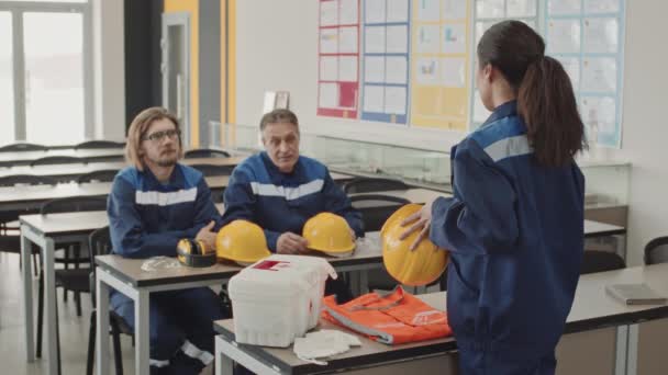 中等速度慢的女工带着黄色硬礼帽坐在课桌上 向男同事解释生产设施安全的安全规则 — 图库视频影像