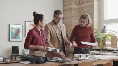 Orta PAN, deneyimli mimarlardan oluşan bir ekiple birlikte modern ofis masasındaki çalışma masasının 3 boyutlu planına bakarak iki katlı ev yapımı ve tasarımı planlarını tartışırken çekildi.