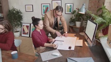 Önemli bir proje üzerinde çalışan erkek ve kadın mimarlardan oluşan yavaş bir ekiple çekim yapıyoruz. Yeni bir ev tasarımı yaratıyoruz. Şık bir ofiste, duvarlarda soyut tablolar var.