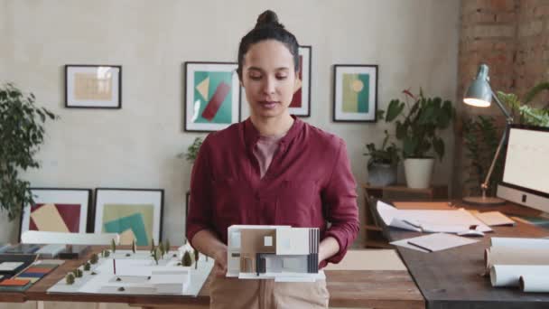 现代风格建筑办公室中女性建筑师手持3D纸制房屋布局摆设相机的中像 — 图库视频影像