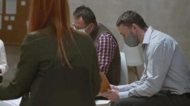 Farklı yaşlardaki erkek ve kadınların çeşitli zihinsel sağlık sorunları olan PAN orta boy fotoğrafları destek grubu toplantısında bir arada otururken yüz maskeleri takıyorlar.