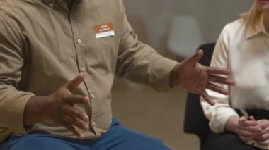 Psikiyatri merkezindeki akıl sağlığı destek grubu toplantısında hikayesini anlatırken aktif olarak el kol hareketi yapan Afrikalı Amerikalı bir adamın orta bölümü.