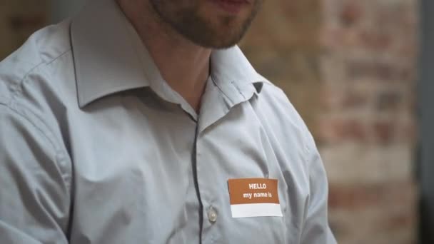 精神的な問題がシャツに名前のタグを添付し サポートグループ会議で彼の話を伝えると落ち込んで男の傾きアップ — ストック動画