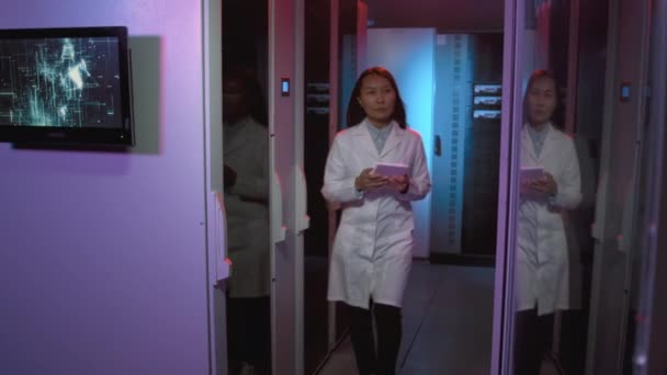 跟踪照片 身穿实验室外套 手持平板电脑 在数据中心行走 然后检查交换机或其他计算机设备的亚洲女网络工程师 — 图库视频影像