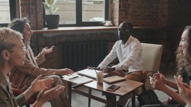 Çeşitli erkek ve kadın iş adamlarından oluşan yavaş bir grup, önemli projenin başarısını kutluyor, el çırpıyor ve modern iş yerinde birbirlerine beşlik çakıyor.