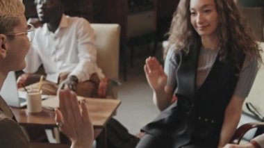 Modern tavan arasında beyin fırtınası yaparken iyi fikirler bulduktan sonra genç neşeli iş arkadaşlarının orta yavaş bir şekilde birbirlerine beşlik çakması.