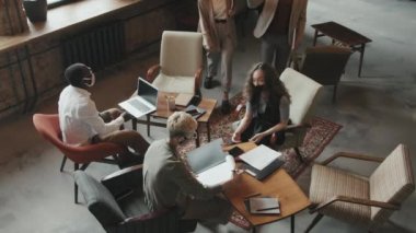 Yüz maskesi takan genç ve çok ırklı insanların üst düzey yavaşlaması temassız bir şekilde modern çatı katı tarzı çalışma alanına gelen iş toplantılarına katılıyor.