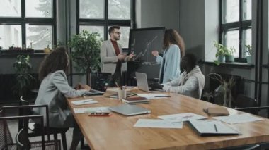 Modern konferans odasındaki şirket toplantısında başarılı sonuçlar tartışan çok ırklı genç iş arkadaşlarının orta derece yavaşlaması