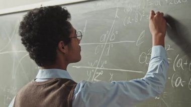 Sert Geometri problemini çözerken, tahtada duran akıllı melez öğrencinin yavaş çekim görüntüsü