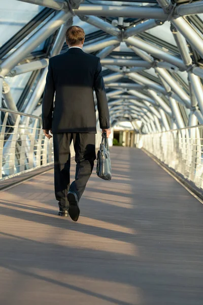 黒い革のハンドバッグを持つビジネスマンの後ろに長い歩道を歩く — ストック写真