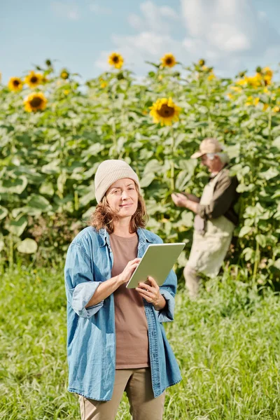 Érett Női Farmer Munkaruhában Áll Kamera Előtt Touchpad Ellen Napraforgó — Stock Fotó