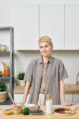 Kahvaltı hazırlamak için mutfaktaki masanın başında duran genç bayan.