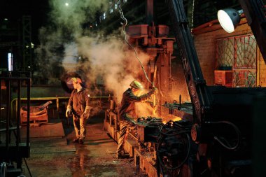 Fabrikada metalle çalışan bir grup işçi.
